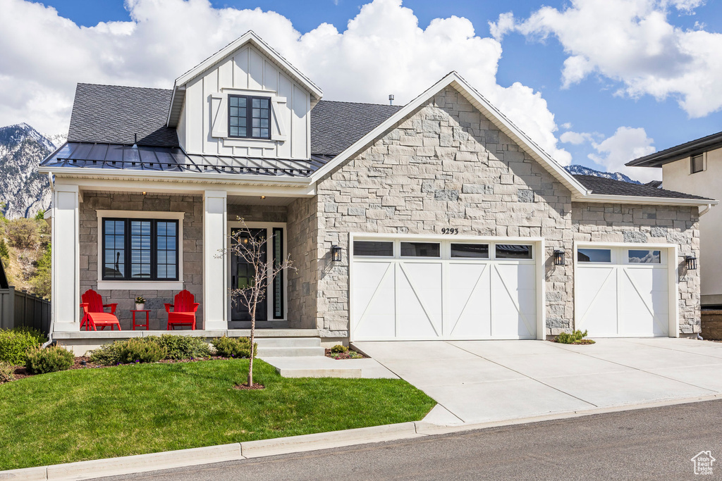 View of front of property featuring concrete driveway, stone siding, a porch, and an attached garage