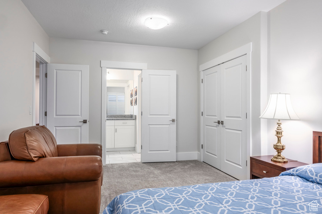 Bedroom featuring light colored carpet, a closet, connected bathroom, and baseboards