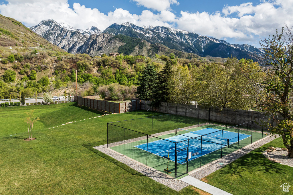 View of pool featuring a yard, a mountain view, fence, and a tennis court