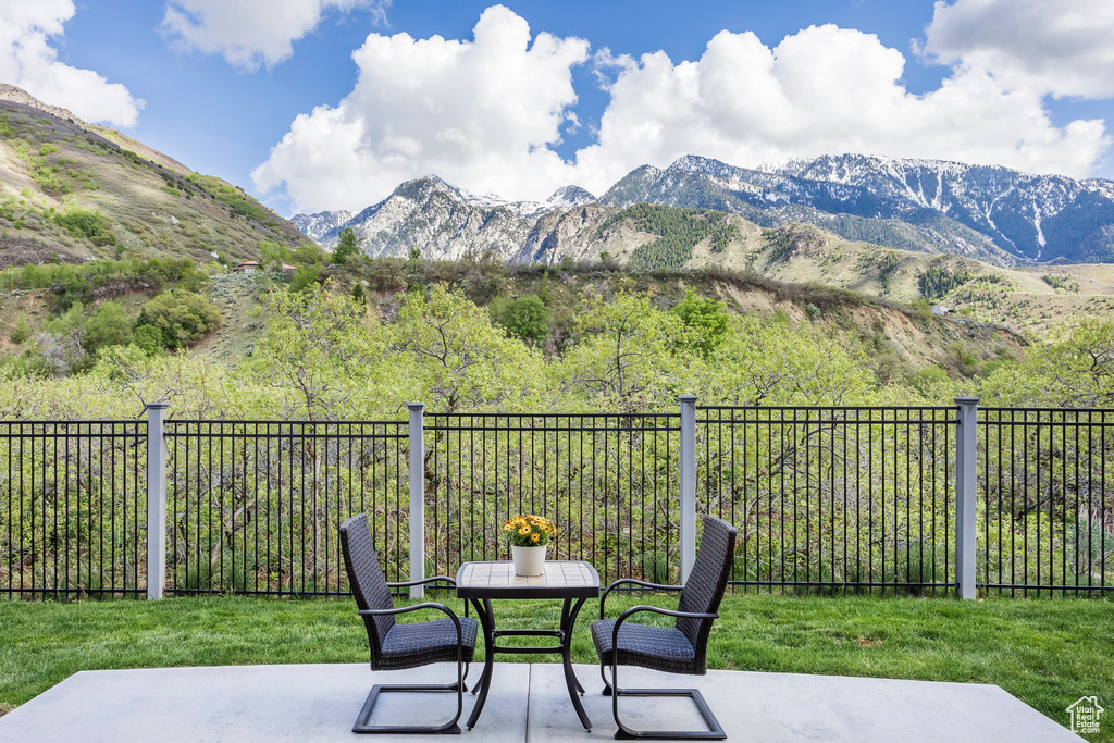 View of patio with a mountain view, outdoor dining area, and fence