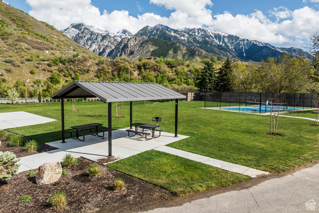 View of community with a lawn, a mountain view, fence, a swimming pool, and a gazebo