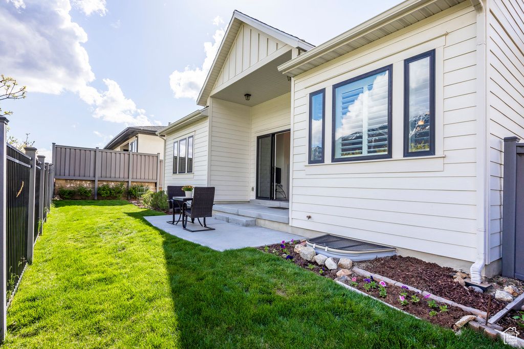 Rear view of property with a yard, board and batten siding, a patio, and a fenced backyard