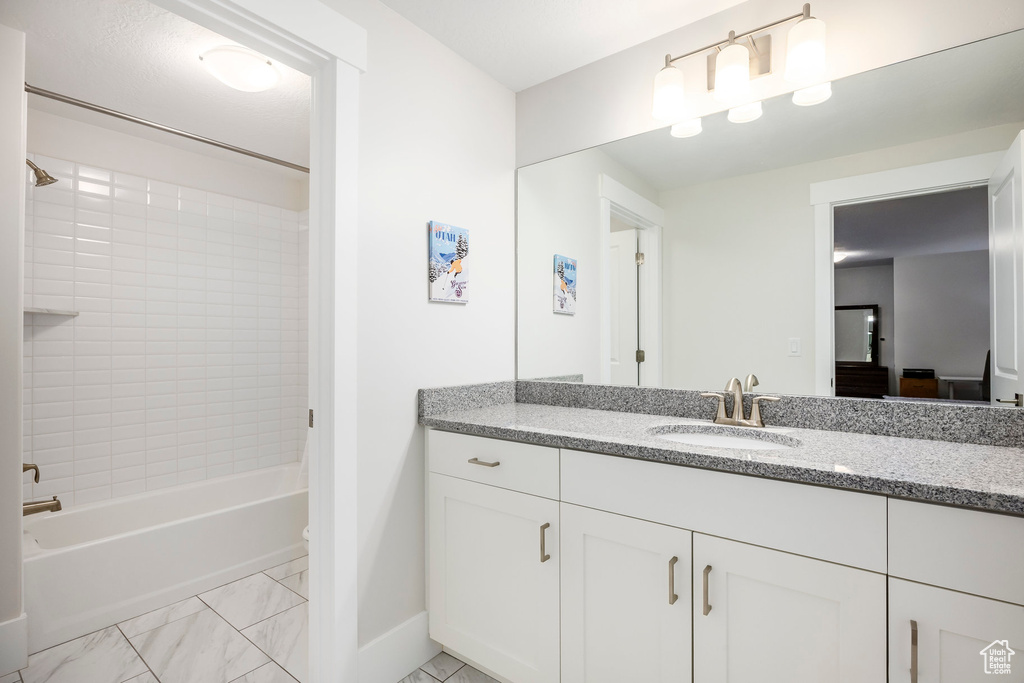 Full bathroom featuring bathtub / shower combination, marble finish floor, baseboards, and vanity
