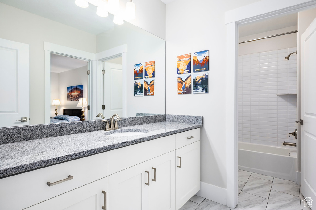Full bath with baseboards, marble finish floor, connected bathroom, vanity, and bathing tub / shower combination