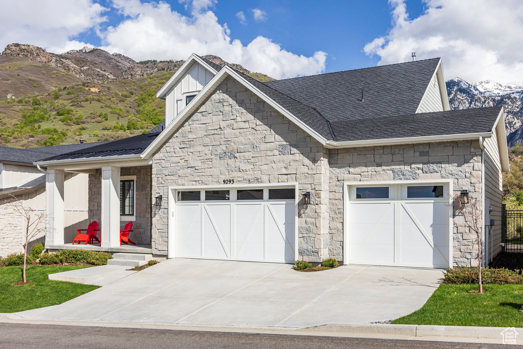 View of front of home with stone siding, concrete driveway, a garage, and board and batten siding