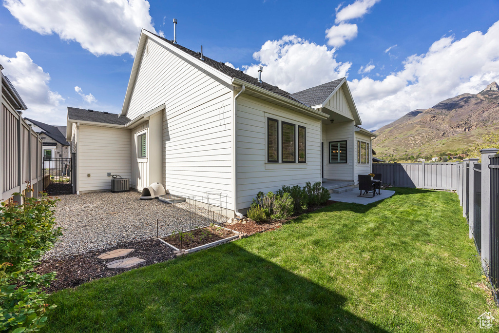 Rear view of property with a fenced backyard, a patio area, a mountain view, and a yard