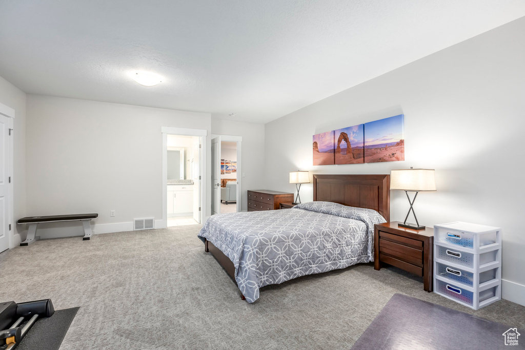 Carpeted bedroom featuring baseboards, ensuite bath, and visible vents