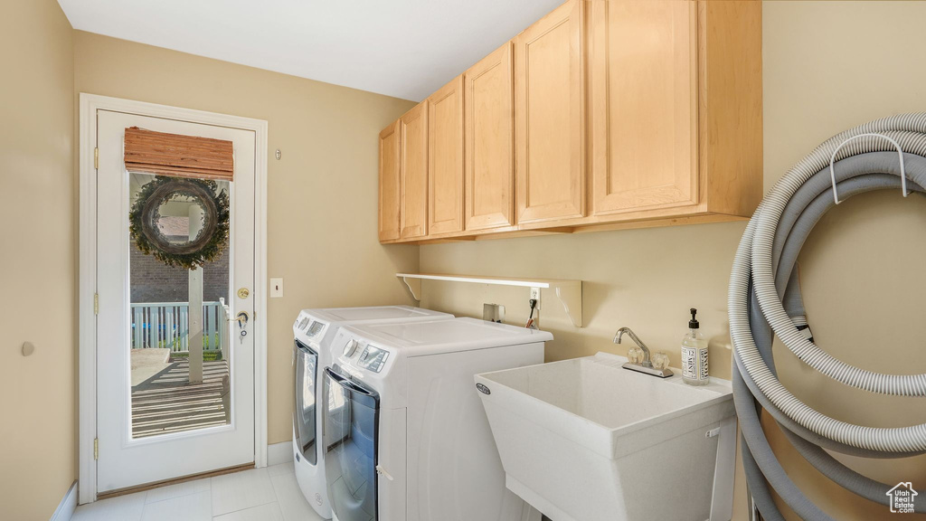 Laundry area with light tile patterned floors, cabinet space, a sink, and washer and clothes dryer