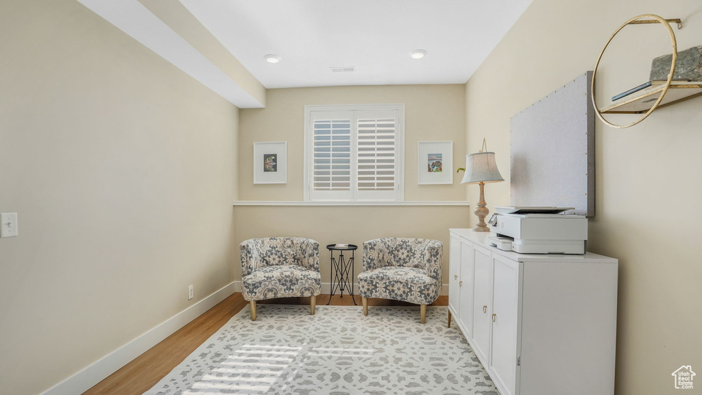 Sitting room featuring visible vents, wood finished floors, baseboards, and a wall unit AC