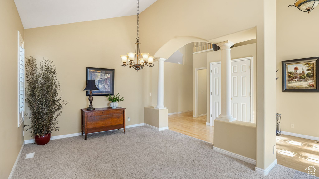 Interior space featuring carpet flooring, an inviting chandelier, decorative columns, high vaulted ceiling, and arched walkways