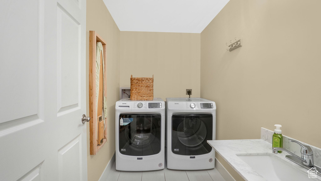 Laundry room with washing machine and clothes dryer, laundry area, light tile patterned floors, and a sink