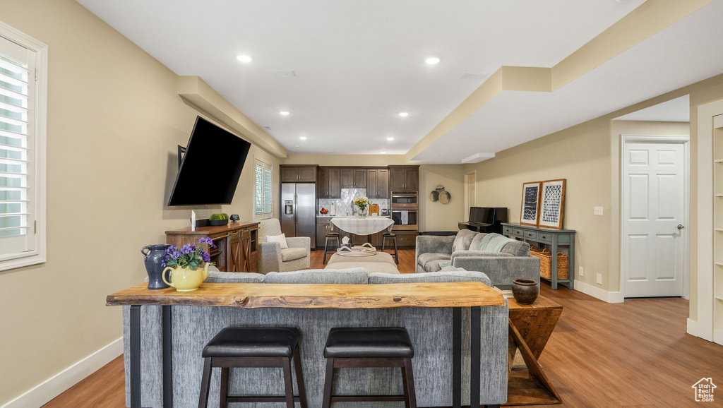 Living room featuring baseboards, recessed lighting, and light wood-type flooring