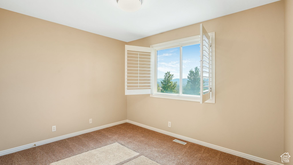 Unfurnished room with carpet flooring, visible vents, and baseboards
