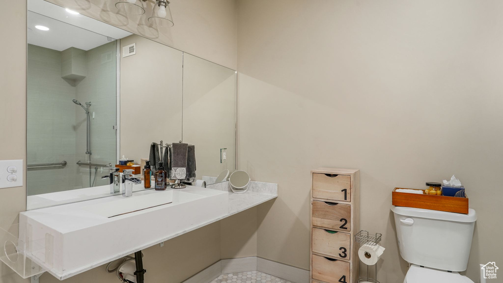 Bathroom with toilet, visible vents, baseboards, and tiled shower