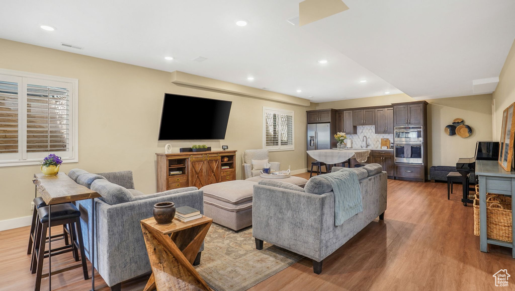 Living area with baseboards, light wood finished floors, and recessed lighting