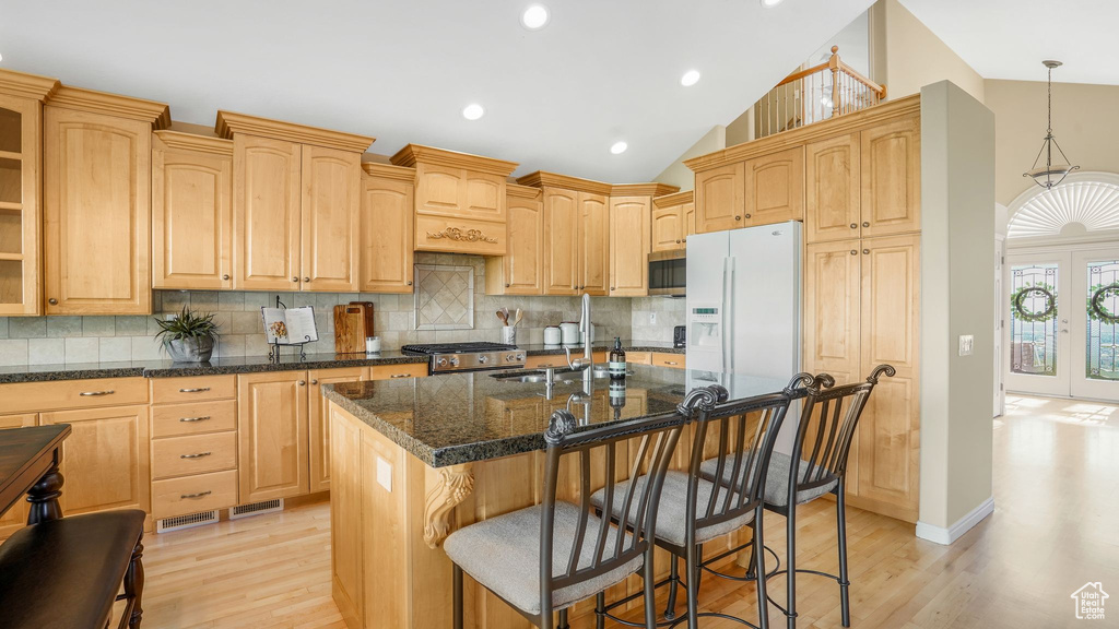 Kitchen with stainless steel microwave, a sink, white fridge with ice dispenser, and light wood-style floors