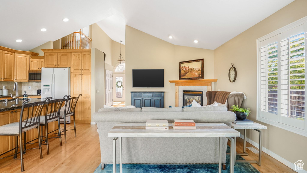 Living area with recessed lighting, light wood-type flooring, baseboards, and a glass covered fireplace