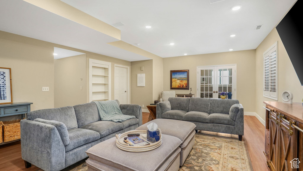 Living room featuring french doors, wood finished floors, built in features, baseboards, and recessed lighting