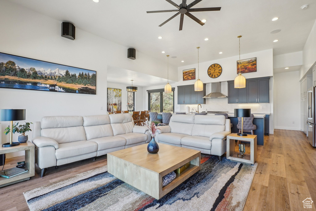 Living area with light wood-type flooring, baseboards, a ceiling fan, and recessed lighting