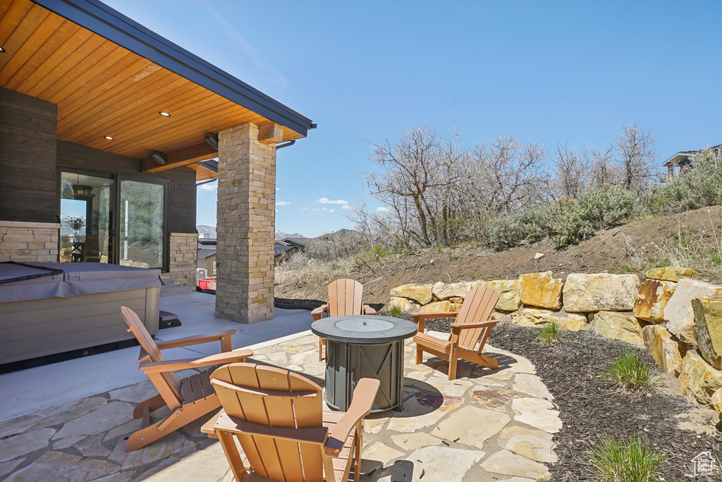 View of patio with an outdoor fire pit and a hot tub