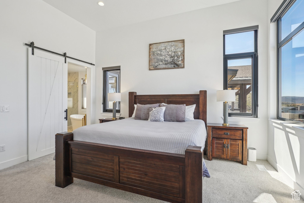 Carpeted bedroom featuring ensuite bath, a barn door, baseboards, and recessed lighting
