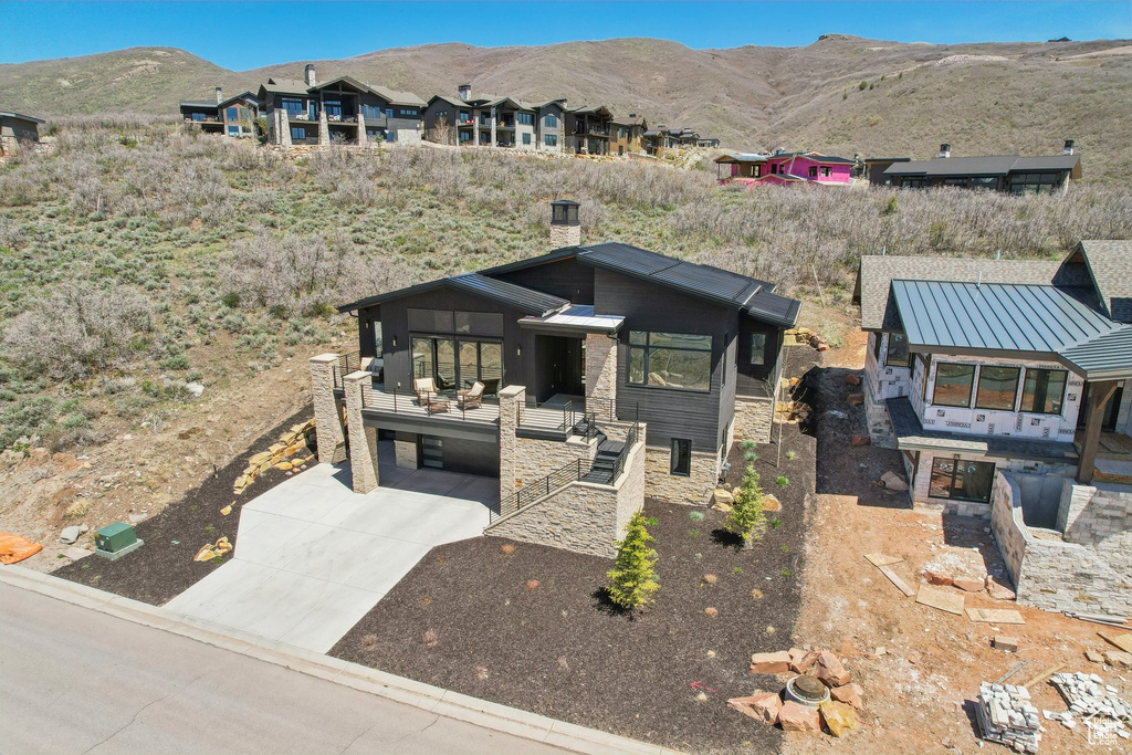 View of front of house with stone siding, a mountain view, driveway, and a carport
