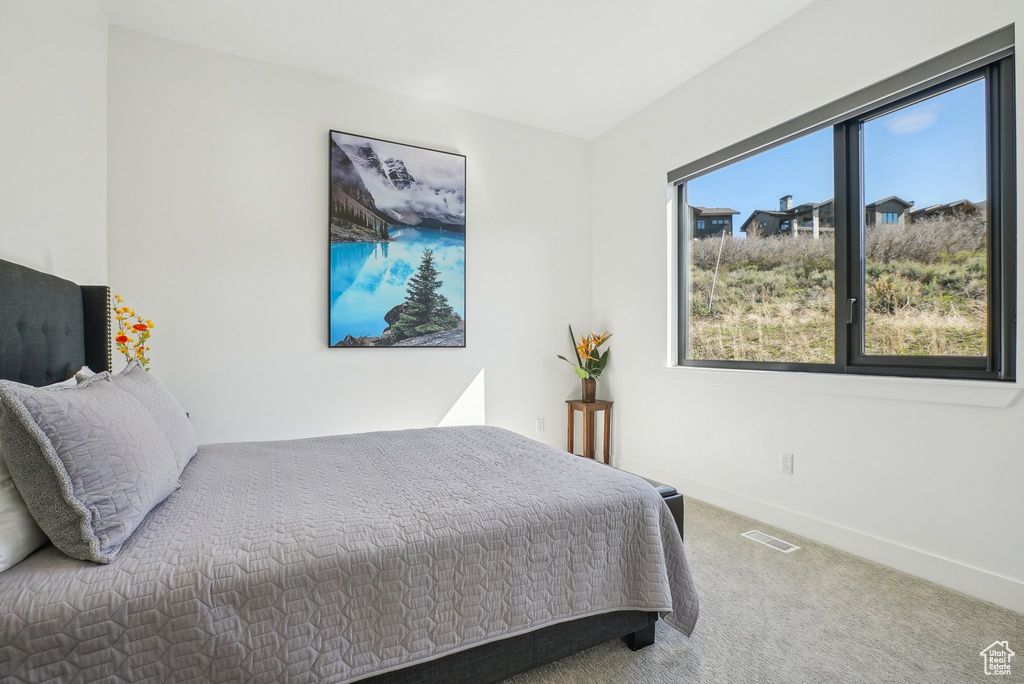 Carpeted bedroom featuring baseboards and visible vents