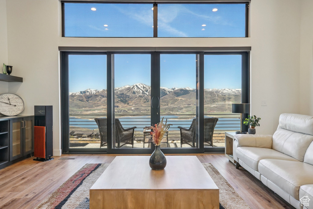 Living room featuring a water and mountain view, wood finished floors, and a healthy amount of sunlight