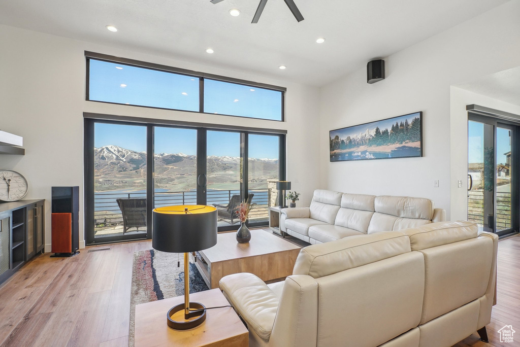 Living room with recessed lighting, light wood-style flooring, ceiling fan, and a high ceiling
