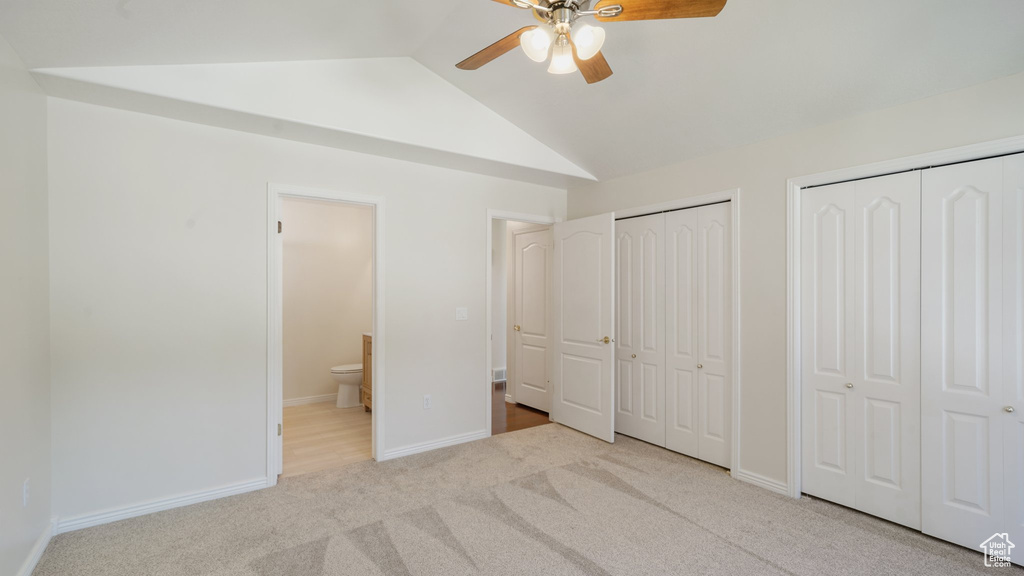 Unfurnished bedroom with ceiling fan, carpet floors, two closets, baseboards, and vaulted ceiling
