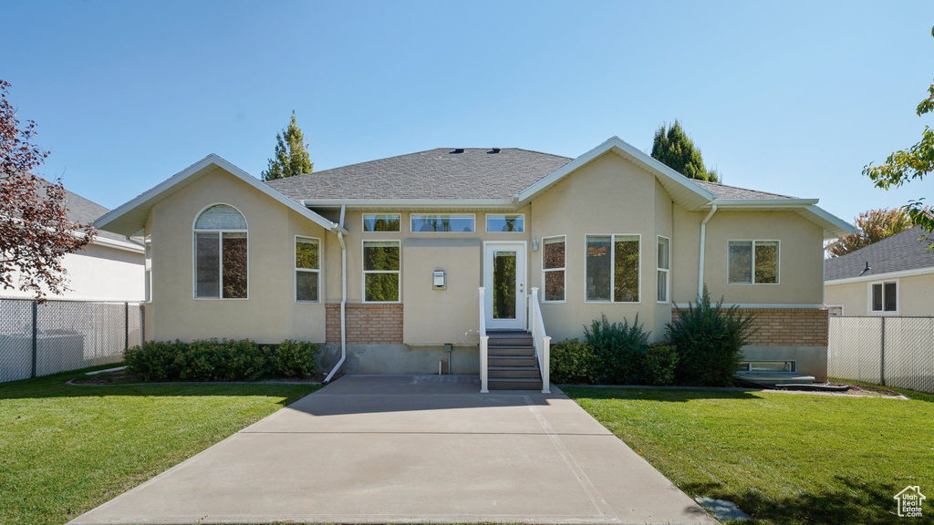 View of front facade featuring fence, stucco siding, a front lawn, and brick siding
