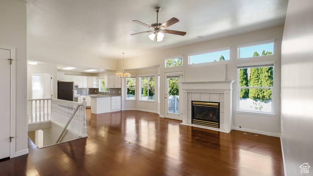 Unfurnished living room featuring a fireplace, a wealth of natural light, and dark wood-type flooring
