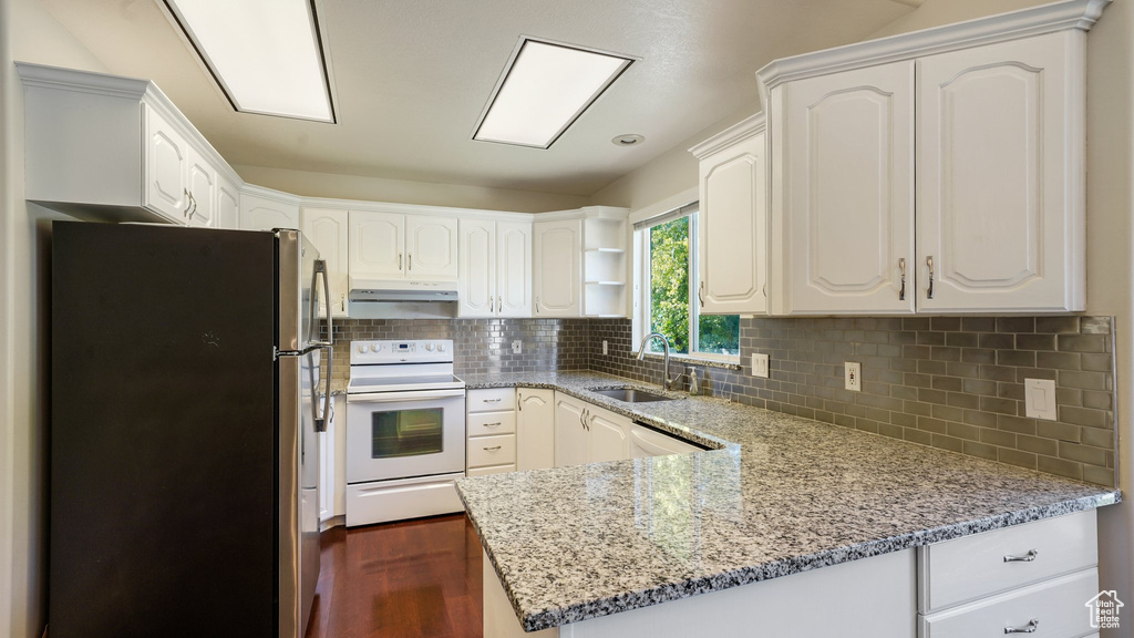 Kitchen featuring open shelves, a sink, white appliances, a peninsula, and under cabinet range hood