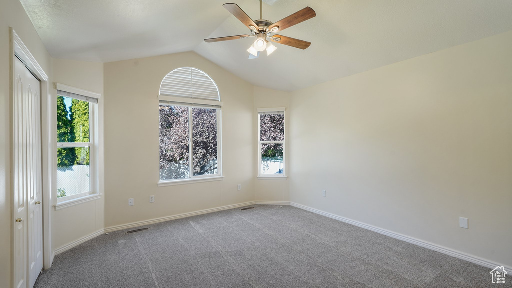 Unfurnished room featuring visible vents, lofted ceiling, baseboards, ceiling fan, and carpet flooring