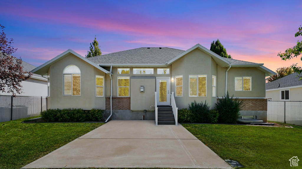 View of front of property with fence, stucco siding, a yard, and brick siding