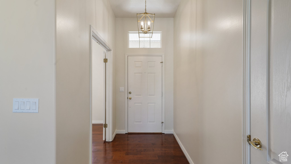 Doorway to outside featuring baseboards, a notable chandelier, and dark wood-style floors