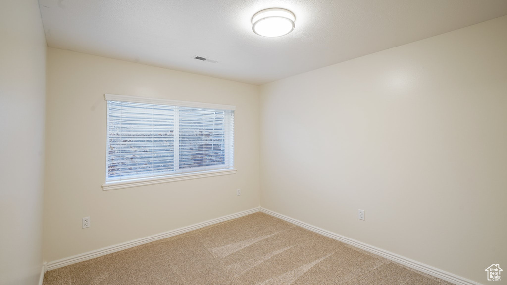 Carpeted spare room featuring baseboards and visible vents