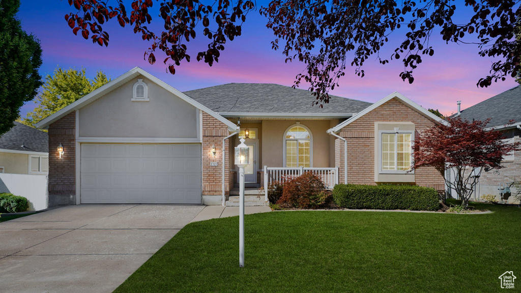Ranch-style house featuring a front lawn, a garage, stucco siding, concrete driveway, and covered porch