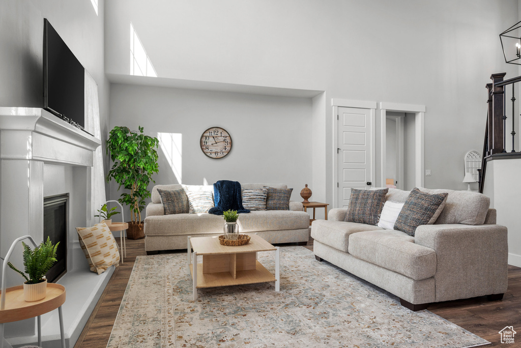 Living room featuring dark wood-style flooring, a high ceiling, and a glass covered fireplace