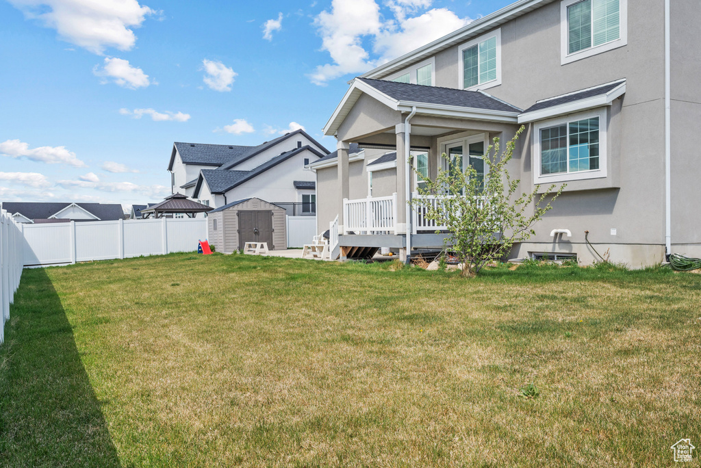 Rear view of house featuring a fenced backyard, stucco siding, a shed, a lawn, and an outbuilding