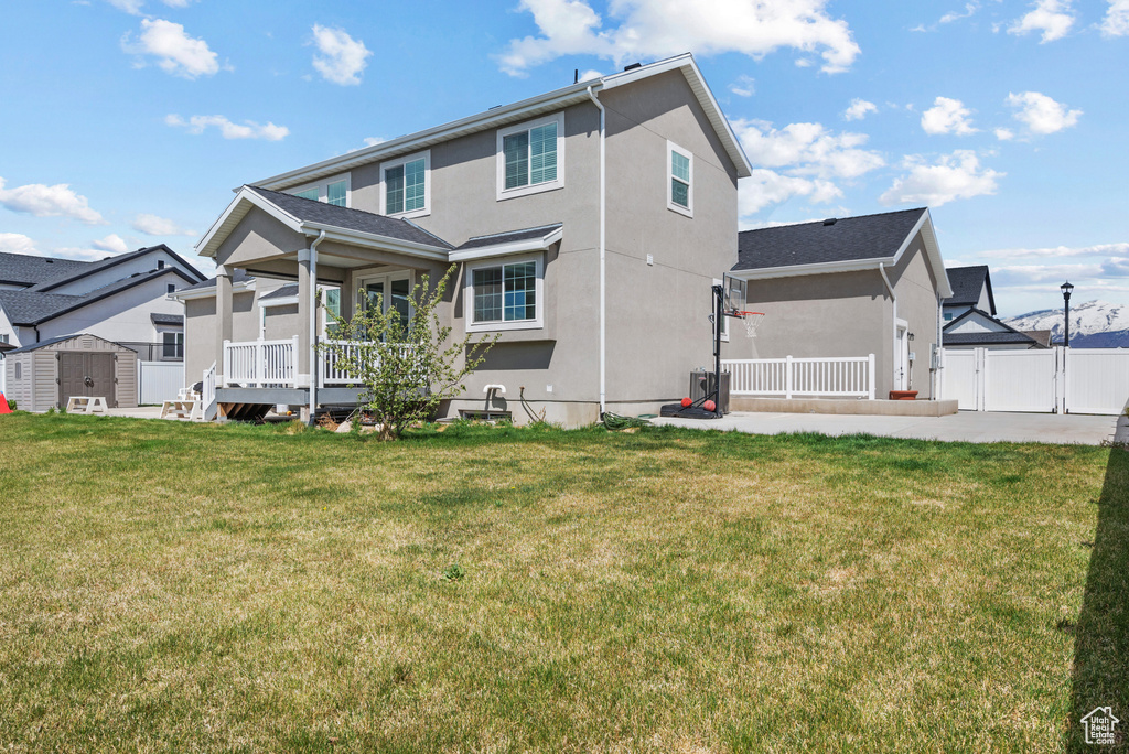 Rear view of property featuring a storage shed, fence, an outdoor structure, and stucco siding