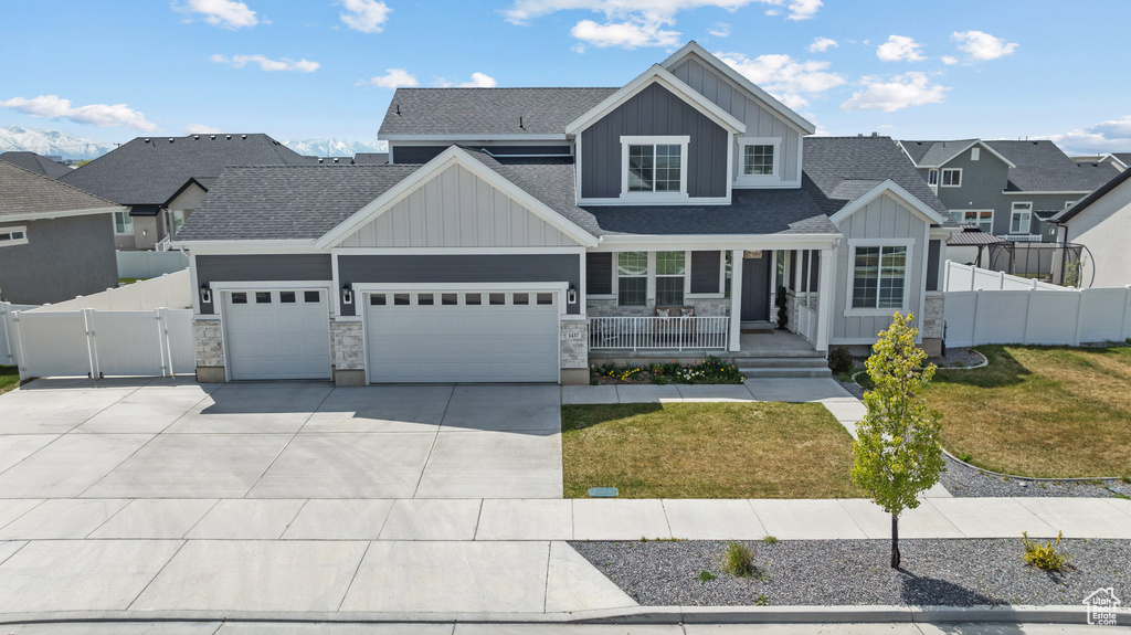 View of front facade featuring covered porch, a gate, board and batten siding, an attached garage, and driveway