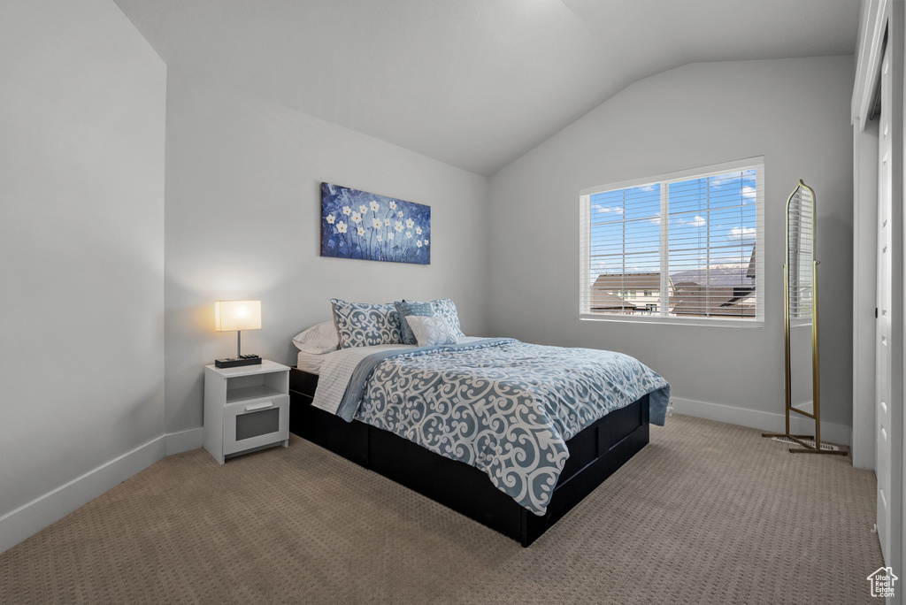 Bedroom featuring baseboards, vaulted ceiling, and carpet