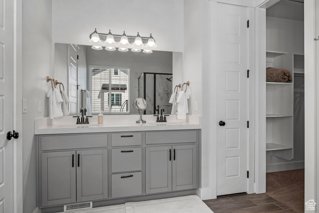 Bathroom featuring visible vents, a sink, a stall shower, and double vanity