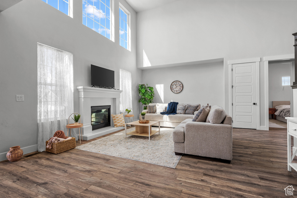 Living area featuring dark wood-style flooring, a glass covered fireplace, and a towering ceiling