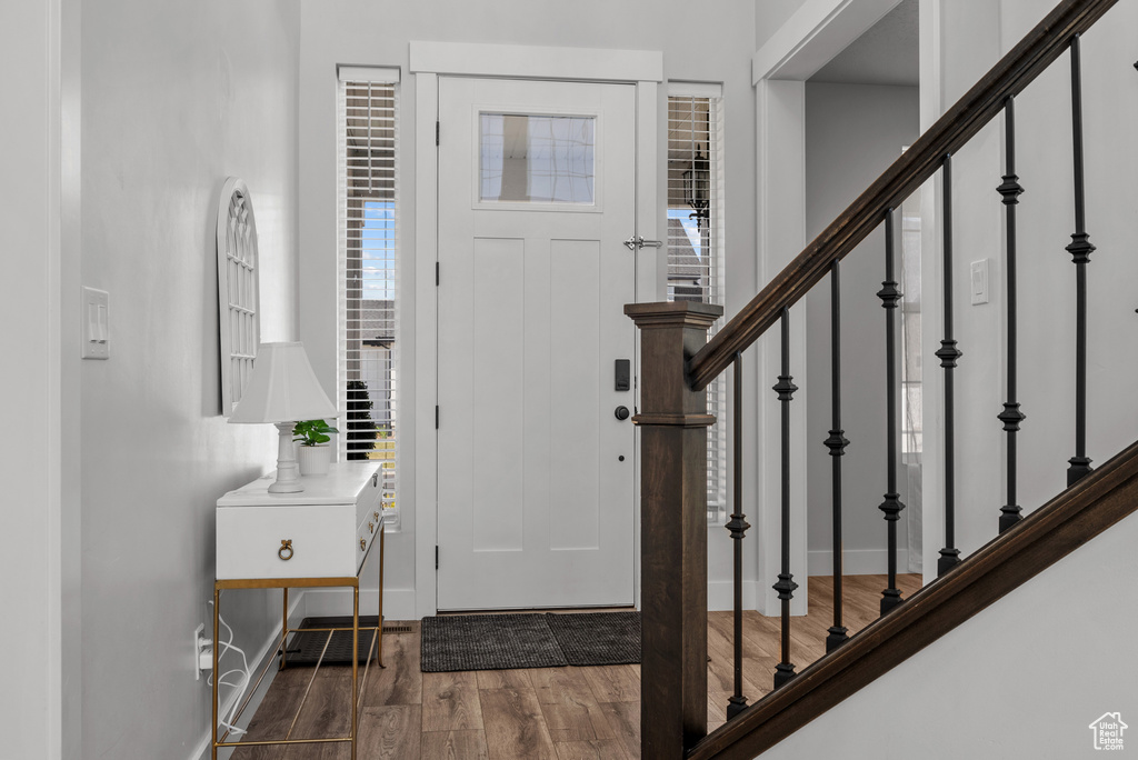 Foyer featuring baseboards, stairs, and wood finished floors