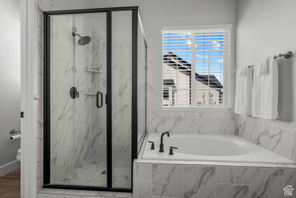 Bathroom featuring a garden tub, a marble finish shower, and toilet