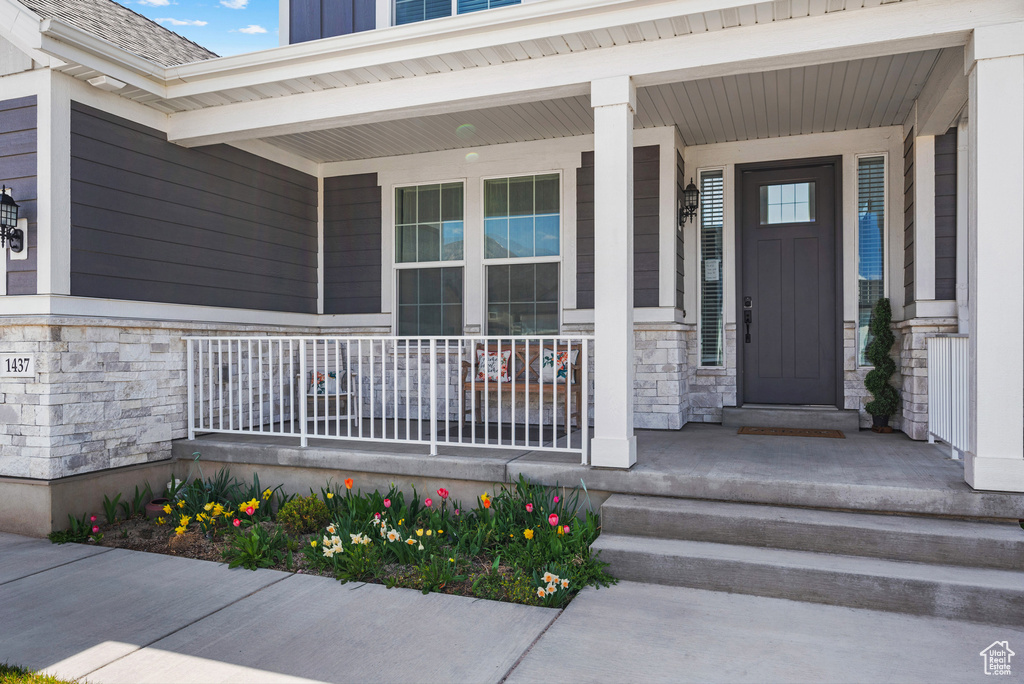 View of exterior entry with a porch and stone siding