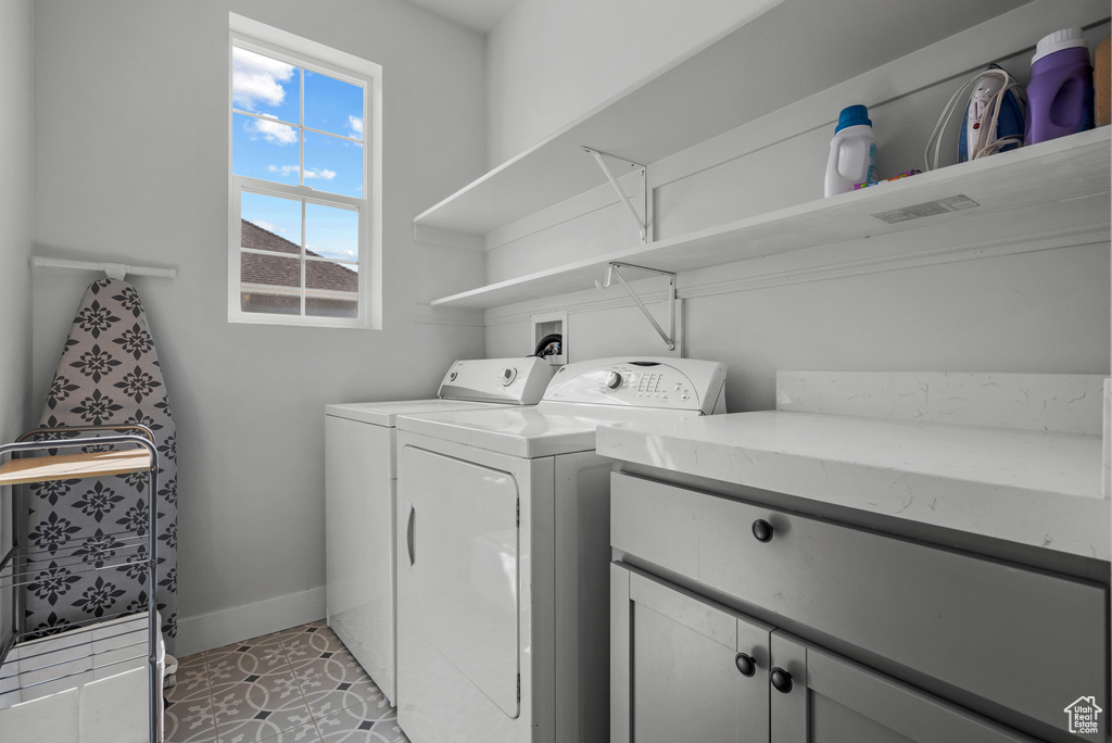 Clothes washing area with baseboards, cabinet space, and washing machine and dryer
