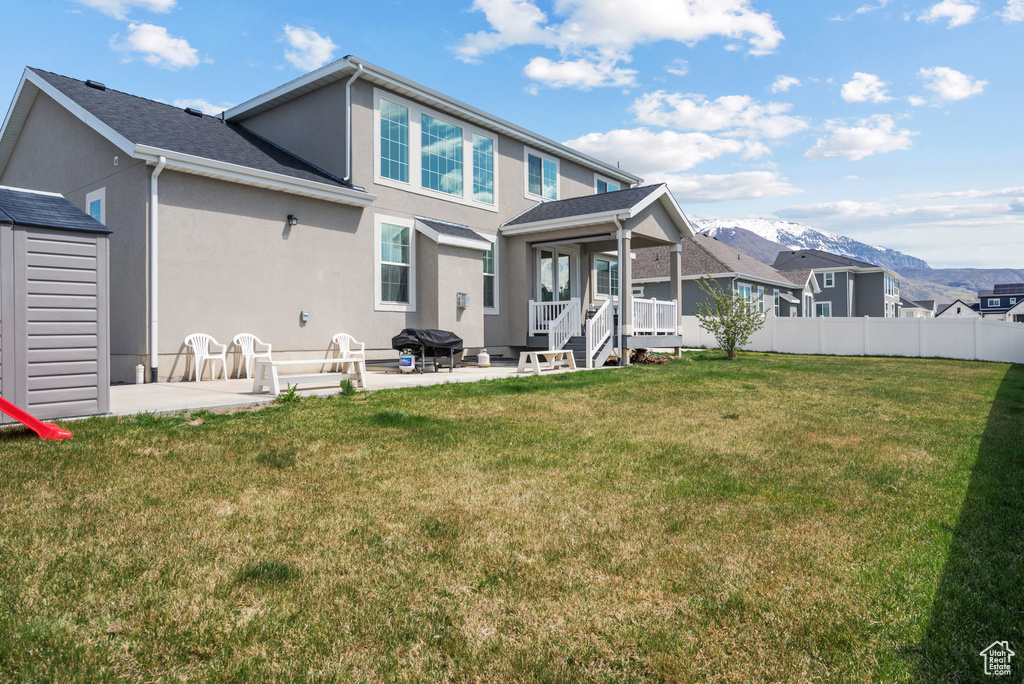 Back of house featuring a patio area, stucco siding, a yard, and a mountain view